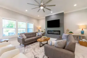 Modern living room with gray sofas and a wall-mounted TV above a sleek fireplace.