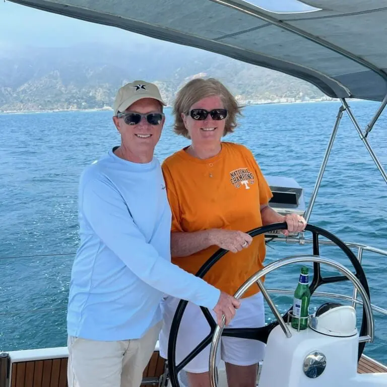 A couple steering a boat, enjoying a sunny day on the water.