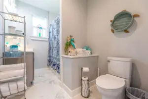 Bright bathroom with white fixtures and a decorative mirror.